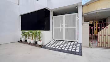 A modern building with a gated entrance, potted plants, and a tiled entrance area.