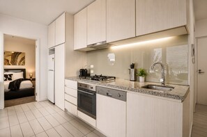 A modern kitchen with a central island, built-in oven, and stainless steel appliances. - Docklands Rooftop Pool Retreat (Docklands)