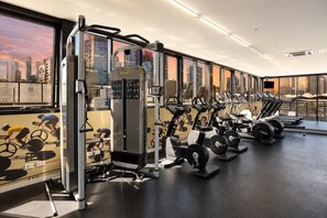 A gym with exercise equipment, large windows, and a city view. - Blue Haven Docklands 2 Bedroom (Docklands)