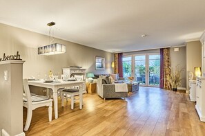 A spacious living area with a dining table, sofas, and a view of the outdoors. - Holiday apartment with 2 bedrooms (Westerland)