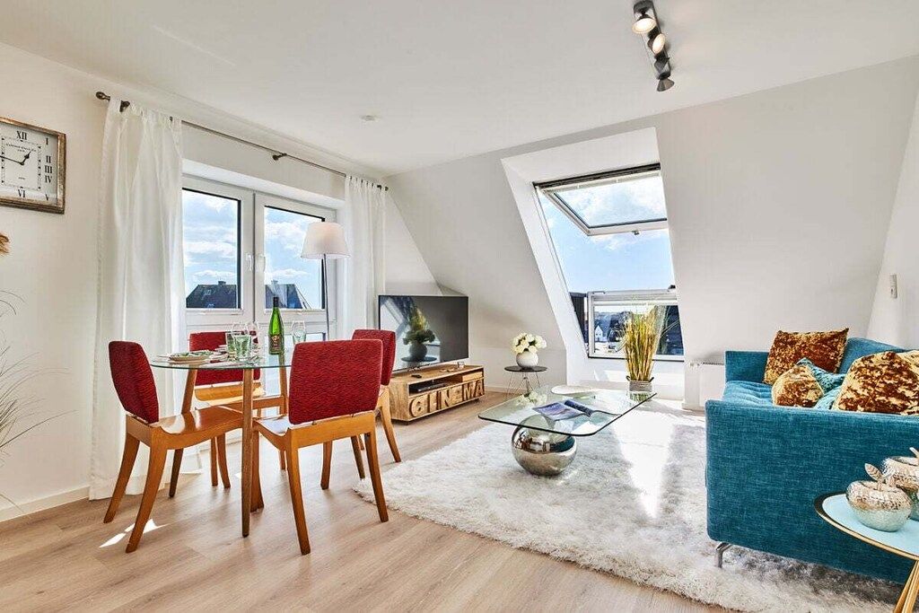 A modern living room with a dining area, a sofa, and a television.