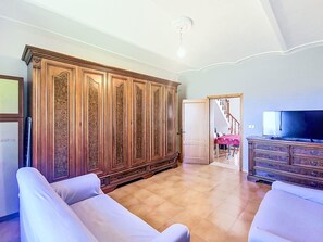 Een ruime woonkamer met een grote houten kast, een televisie en een trap naar een andere kamer.