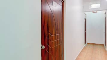 Un pasillo con una puerta de madera marcada con el número 213, que conduce a una habitación con piso de madera.