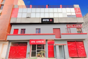 A hotel with a red and grey facade, a prominent sign for 'Hotel Aastha Inn,' and a visible 'OYO' logo. - Hotel O Aastha Inn (Lucknow)