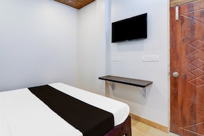 A bedroom with a bed, a mounted TV, a wall-mounted shelf, and a door. - Hotel O Aastha Inn (Lucknow)