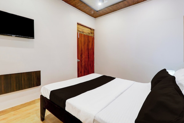 A bedroom with a bed, a television mounted on the wall, and a wooden ceiling. - Hotel O Aastha Inn (Lucknow)
