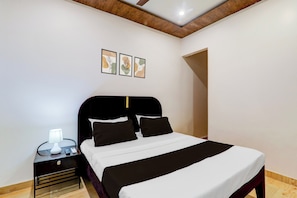 Un dormitorio moderno con cama, mesita de noche, lámpara y tres cuadros en la pared.
