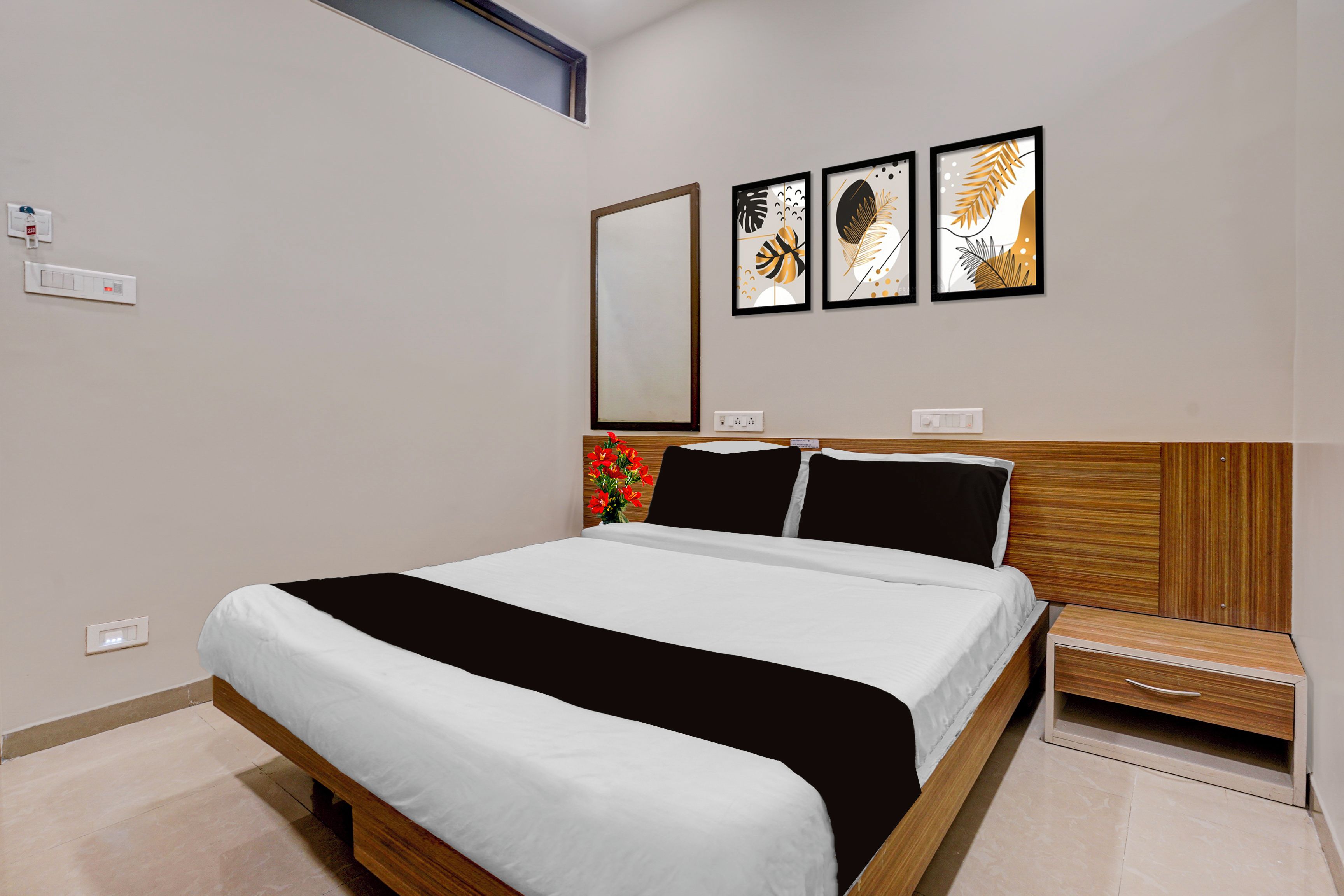 Un dormitorio moderno con una cama grande, una mesita de noche, un espejo y tres cuadros en la pared.
