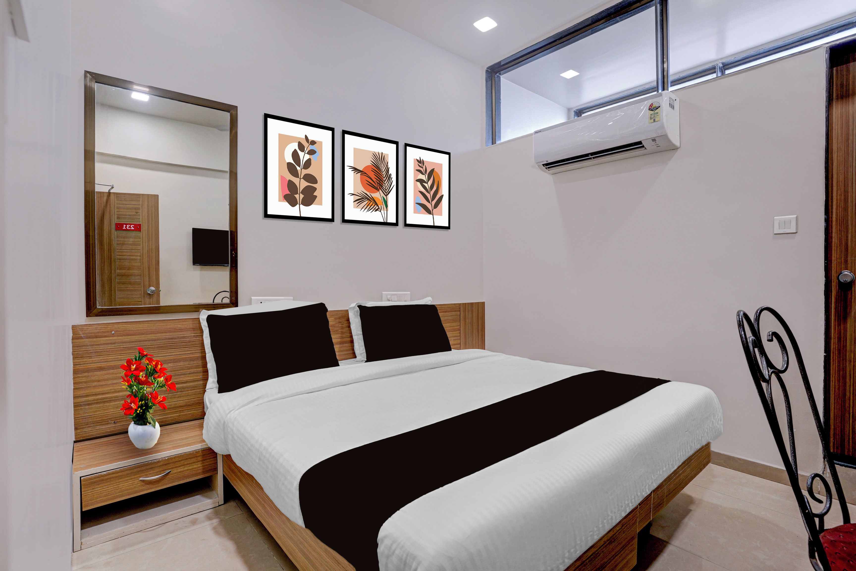 Un dormitorio con cama, mesita de noche, espejo y aire acondicionado instalado en la pared.
