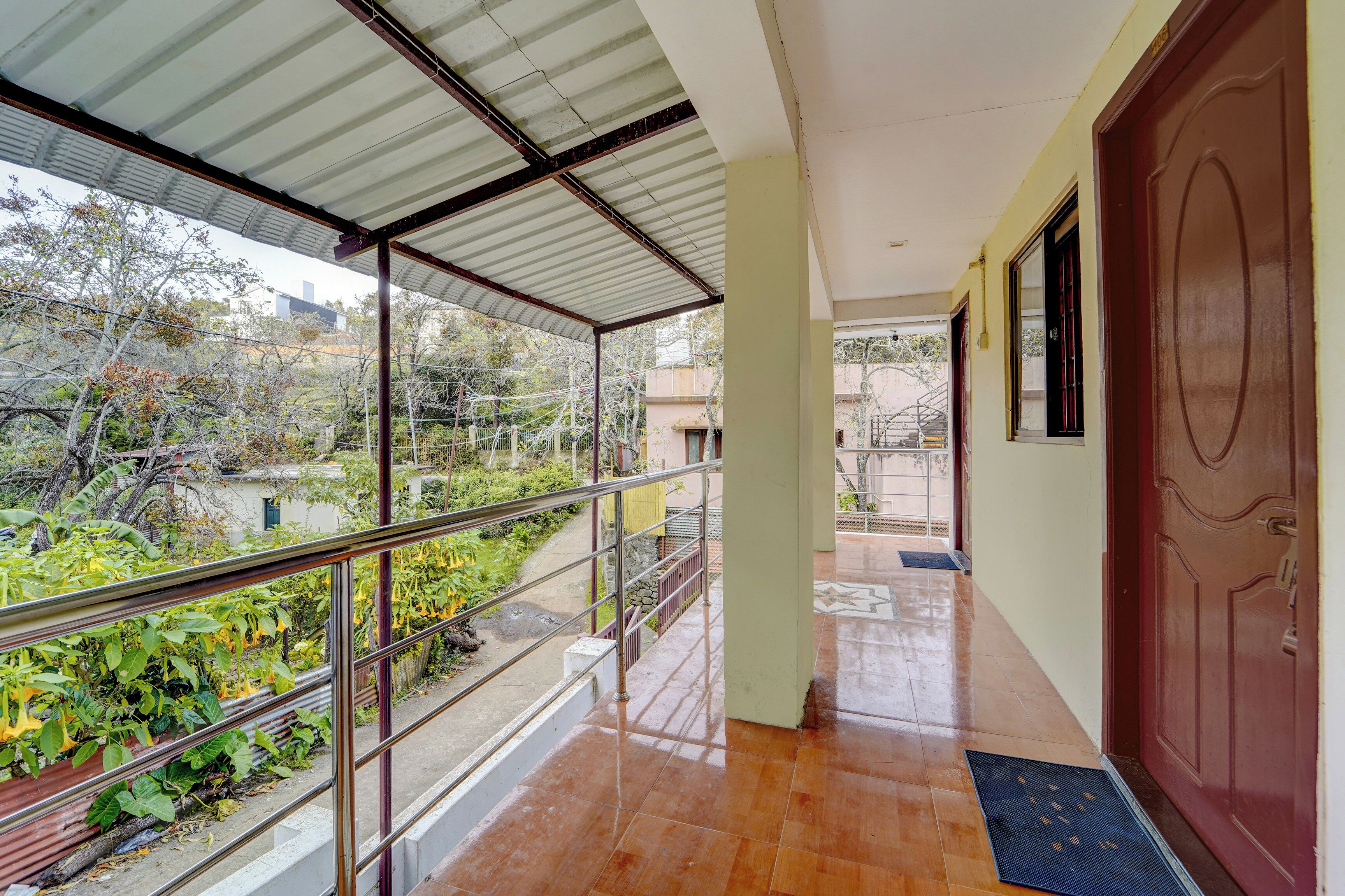 Corredor com guarda-corpo de metal, piso de azulejos e vista para o verde lá fora.