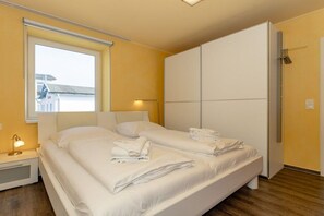 A hotel room with a bed, a bedside table, a lamp, a wardrobe, and a window. - Holiday apartment Villa Patricia 319558 (Kühlungsborn-Ost)