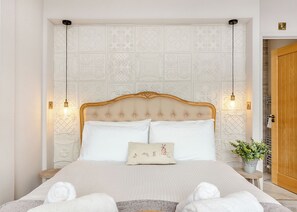 A neatly made bed with a decorative headboard, two bedside lamps, and a pillow with a rabbit design. - 1 bedroom accommodation in Invermoriston (Invermoriston)