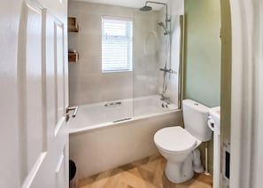 Une salle de bain avec une baignoire, des toilettes et une fenêtre.
