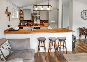 Eine moderne Küche mit einer Holz-Kochinsel, Barhocker und einem Essbereich mit einer Couch und Sesseln.
