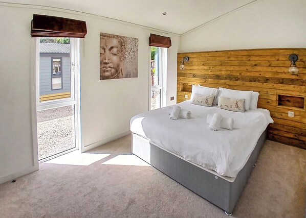 Ein Schlafzimmer mit einem Bett, einem Holzkopfende und einem großen Fenster.