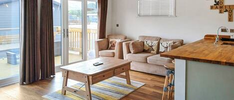 A spacious living area with a wooden coffee table, a sofa set, and a kitchen area with a wooden countertop.