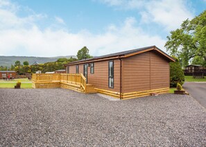 A wooden cabin with a gravel driveway and a wooden deck. - 1 bedroom accommodation in Fort Augustus (Fort Augustus)