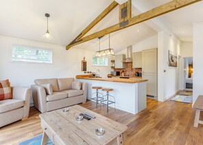 A modern living room with a sofa, coffee table, and a kitchen area with a bar. - 1 bedroom accommodation in Fort Augustus (Fort Augustus)