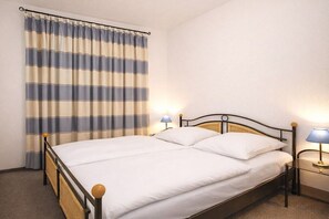 A single bed with a wooden headboard, two bedside lamps, and a striped curtain. - Holiday apartment Haus Meeresblick 319636 (Kühlungsborn - West)