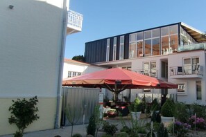 A modern building with a balcony, a red umbrella, and potted plants. - Holiday apartment Villa Patricia 319556 (Kühlungsborn-Ost)
