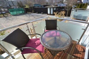 Ein Balkon mit einem Glastisch und zwei Korbstühlen mit Kissen.