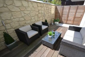 An outdoor patio with wicker furniture, a stone wall, and a wooden fence. - Holiday apartment Villa Patricia 319555 (Kühlungsborn-Ost)