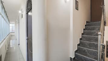 Un pasillo con una escalera, una puerta y un ventanal.