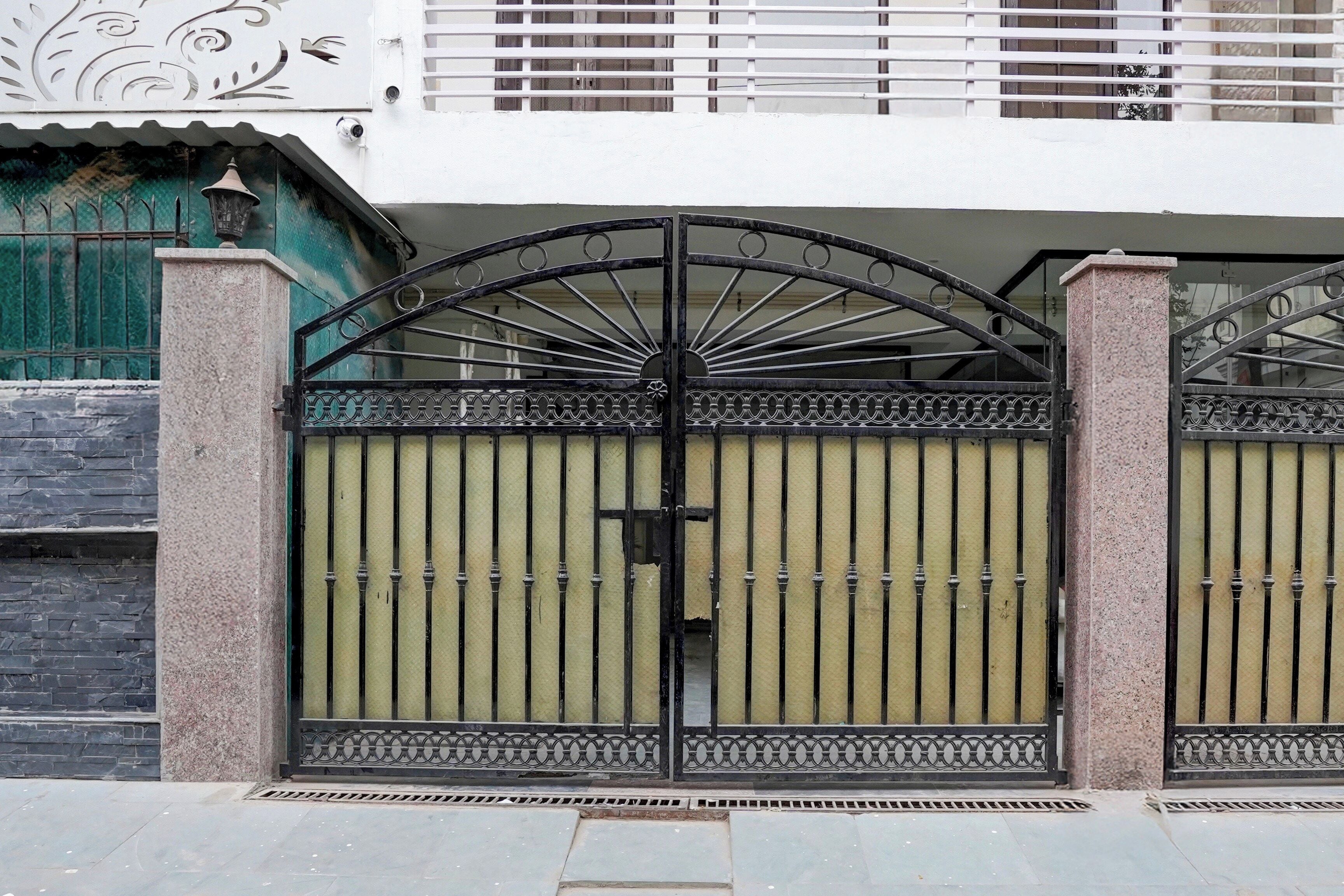Une entrée fermée par un portail en métal décoratif et équipée d’une caméra de surveillance.