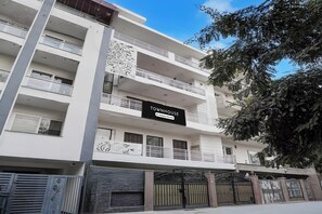 A multi-story building with balconies, a sign reading 'TOURN HOUSE Company Serviced', and a gated entrance. - Townhouse Sector 46 Huda Market (Gurugram)