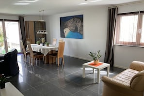 A dining area with a table and chairs, a sofa, a small table with a plant, and a painting on the wall. - Holiday home in Schweich with swimming pool (Schweich)