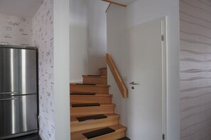 A staircase with wooden steps and a metal handrail, leading to a white door. - Holiday home in Schweich with swimming pool (Schweich)