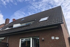 A residential building with a tiled roof, a satellite dish, and a chimney. - Holiday apartment with 2 bedrooms (Norddeich)