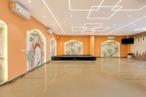 A spacious indoor area with a polished floor, decorative wall murals, and recessed ceiling lighting. - Collection O Lorven Grand (Visakhapatnam)