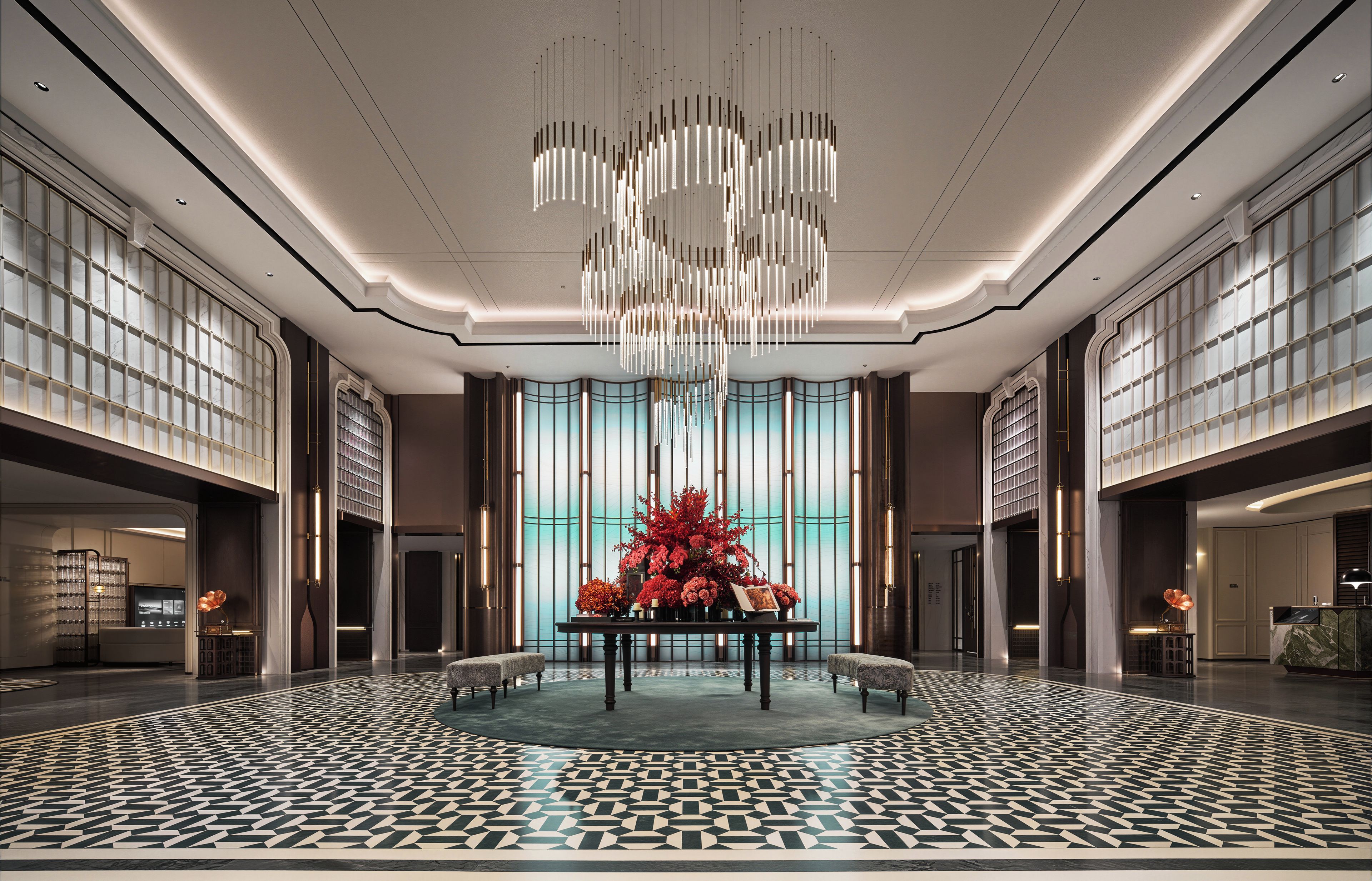 Un hall d’entrée spacieux, agrémenté d’un lustre moderne, d’une composition florale centrale et d’un sol à motifs.