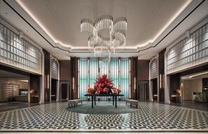 Un hall d’entrée spacieux, agrémenté d’un lustre moderne, d’une composition florale centrale et d’un sol à motifs.