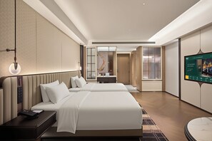 Une chambre d’hôtel moderne équipée d’un lit, de tables de chevet, d’un bureau et d’une télévision.