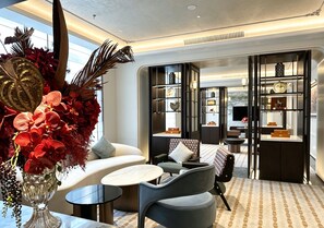 A modern interior with a seating area, a glass table, and a decorative plant arrangement.