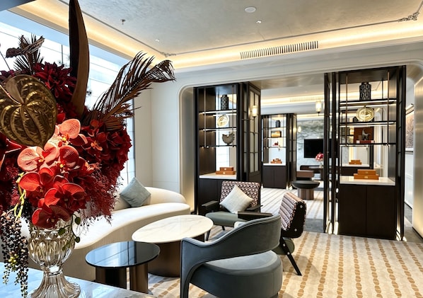 A modern interior with a seating area, a glass table, and a decorative plant arrangement.
