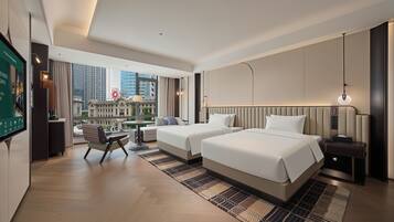 Une chambre d’hôtel moderne avec deux lits, un bureau et une vue sur le paysage urbain.
