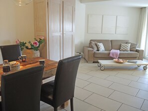 A dining area with a wooden table, chairs, and a vase of flowers. - Fiore Rosa by Interhome (Ascona)