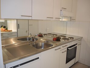Una cocina moderna con electrodomésticos de acero inoxidable, un lavamanos doble y un horno empotrado.