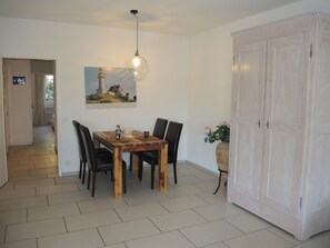 A dining area with a wooden table and chairs, a pendant light, a painting of a lighthouse, and a large white wardrobe. - Fiore Rosa by Interhome (Ascona)