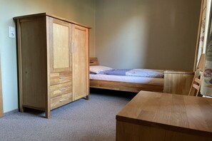 A bedroom with a wooden wardrobe, a single bed, and a small wooden table. - Holiday apartment with 2 bedrooms (Heiligenhafen)