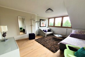 A bedroom with a bed, a chair, a desk, a mirror, a window, and a rug. - Holiday apartment with 1 bedroom (Ostbevern)