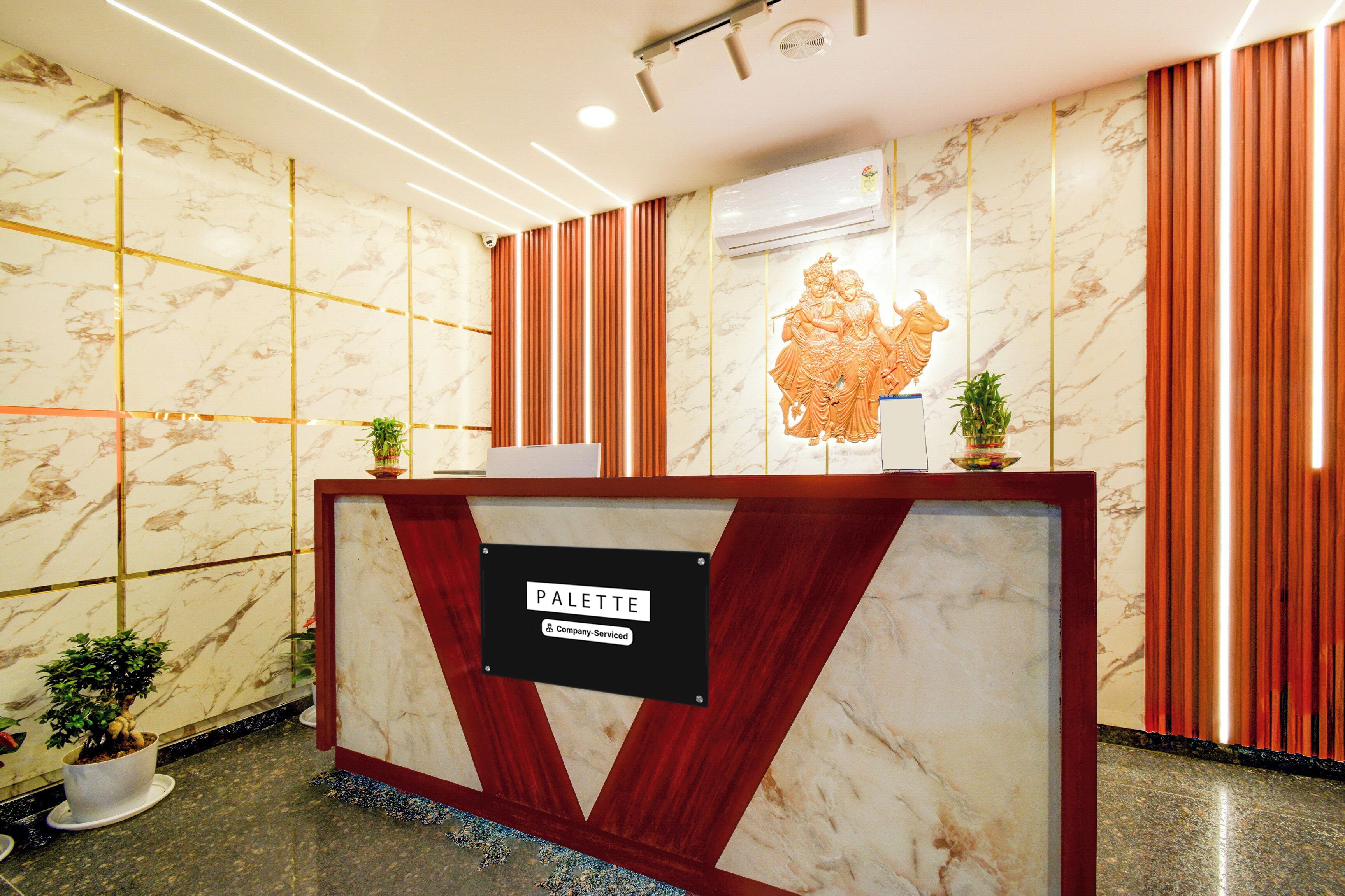 A reception desk with a marble finish, a company-serviced sign, and a decorative relief sculpture above it.