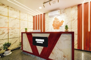Una taquilla de recepció amb acabat de marbre, un senyal de servei de l'empresa i un relleu decoratiu a la part superior.