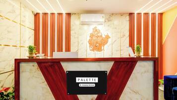 A reception desk with a marble wall, a company-serviced sign, and a decorative relief sculpture.