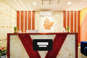 A reception desk with a marble wall, a company-serviced sign, and a decorative relief sculpture. - Hotel O 4 COLORS (Hyderabad)