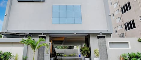 A modern building with a flat facade, large windows, and a covered entrance area with steps leading up to it.
