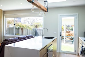 A modern kitchen with a central island, a built-in sink, and a window overlooking a backyard.